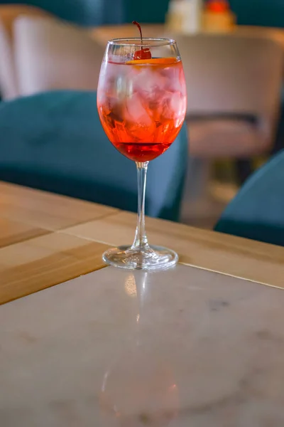 Cocktail rouge avec glace servi dans un verre sur une table en bois avec fond de restaurant flou. Boisson estivale rafraîchissante. — Photo