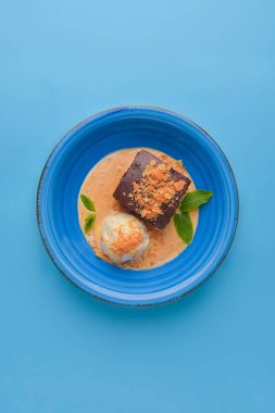 Sıcak çikolatalı vanilyalı dondurma ve pastel mavi arka planda mavi bir kasede sıcak çikolatalı kek. Çay ya da kahve için lezzetli çikolatalı tatlı..