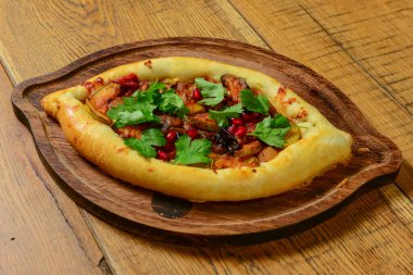 Peynir ve yumurtalı Hhachapuri, ahşap bir masada servis edilen tahta bir tabakta. Geleneksel Gürcistan mutfağı, lezzetli yemekler.