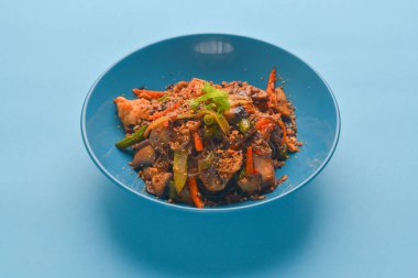 Tavuklu salata ve fırında sebze. Lezzetli ve sağlıklı yemek konsepti. Et salatası ve sos. Mavi bir tabakta servis edilmiş, mavi arka planda..