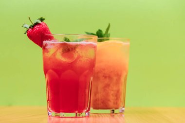 Meyve suyu ve buzlu yaz içecekleri. Yeşil arka planda farklı bardaklarda yaz içecekleri tazeleniyor. Alkol kokteyli konsepti.