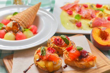 Yeşil ekose masa örtüsünün üzerinde ahşap bir tahtada servis edilen soslu lezzetli meyve somonu bruschetta. Geleneksel İtalyan mutfağı. İtalyan konsepti. Masada balıklı üç bruschetta ekmeği..