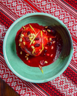 Kuru üzümlü, şekerli ve cevizli nefis bir elma geleneksel Ukrayna kırmızı masa örtüsünün üzerinde servis edilir. Geleneksel tatlı, çay zamanı. Elma şekeri.