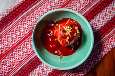 Kuru üzümlü, şekerli ve cevizli lezzetli elma geleneksel kırmızı masa örtüsünün üzerinde servis edilir..