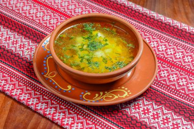 Kırmızı masa örtüsünün üzerinde geleneksel tavuk çorbası tabağı resmi. Lezzetli yemek konsepti. Sağlıklı beslenme, Ukrayna mutfağı kavramı.