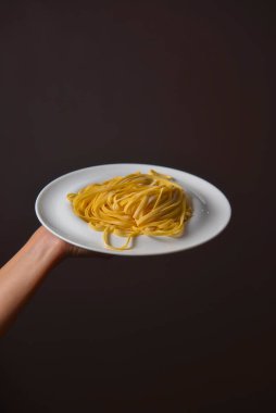 Female hands holding pasta pici over black background. Dark rustic style. Copy space banner. Creative idea concept. Delicious Italian pasta. Cooking concept. clipart