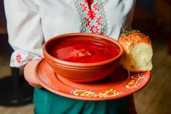 Geleneksel Ukrayna Borsch 'u. Seramik kasede Rus vejetaryen kırmızı çorbası. İşteki garson pancar çorbası servis ediyor. Restoran konseptiyle dışarıda yemek yemek..