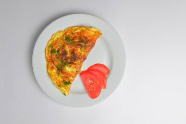 Çırpılmış yumurta, taze otlar ve beyaz arka planda domates. Lezzetli kahvaltı konsepti. Kahvaltıda omlet..