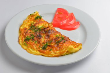 Çırpılmış yumurta, taze otlar ve beyaz arka planda domates. Lezzetli kahvaltı konsepti. Kahvaltıda omlet..
