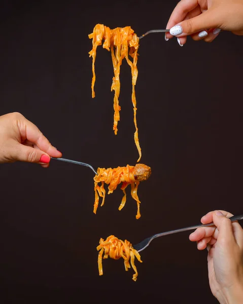 Hands hold homemade pasta in the air over black background. Creative idea. Italian cuisine concept. Traditional dish pasta.