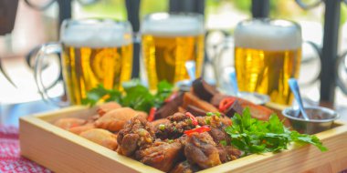 Bira için geniş bir tabak dolusu abur cubur. Arka planda üç bira bardağı var. Restoranda ya da bar dışında yemek yemek. Yaz mevsimi.