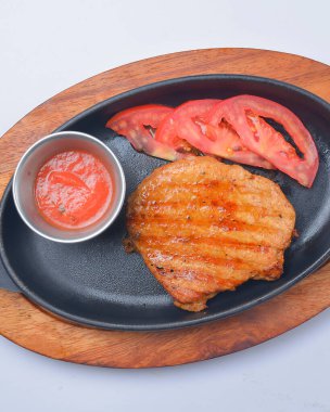 Tavada domates ve sos ile servis edilen kalın bir biftek parçası. Lezzetli et, barbekü konsepti. Akşam yemeği..