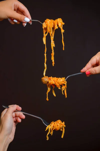 Hands hold homemade pasta in the air over black background. Creative idea. Italian cuisine concept. Traditional dish pasta.