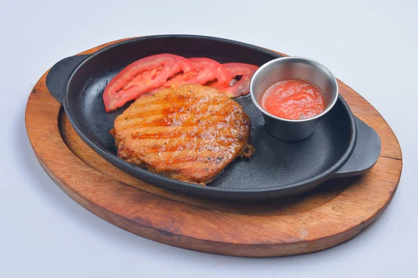 A thick strip steak piece served with tomatoes and sauce in a pan. Delicious bbg meat, barbecue concept. Food for dinner.