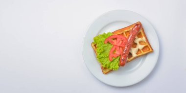 Tabakta kızarmış sosis ve sebzeli ekşi waffle. Lezzetli geleneksel kahvaltı fikri. Viyana waffle 'ı, Belçika waffle tarifi. Beyaz arka plan. Boşluk afişini kopyala.