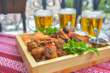 Bira için geniş bir tabak dolusu abur cubur. Arka planda üç bira bardağı var. Restoranda ya da bar dışında yemek yemek. Yaz mevsimi.