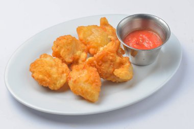 Domates soslu kızarmış tavuk nuggetları. Beyaz arka planda beyaz bir tabakta servis edilmiş. Fast food, abur cubur kavramı.