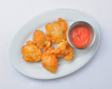 Domates soslu kızarmış tavuk nuggetları. Beyaz arka planda beyaz bir tabakta servis edilmiş. Fast food, abur cubur kavramı.