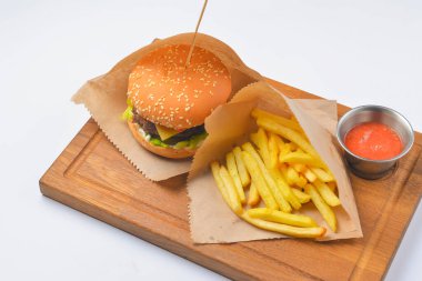 Patates kızartması ve domates soslu hamburger. Fast food, abur cubur konsepti. Beyaz arka planda, ahşap bir tahtanın üzerinde servis edilmiş. Kapat..