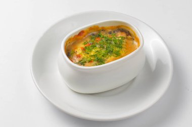 Kavrulmuş sebze, patates, mantar ve peynir bir tencerede. Beyaz bir tencerede yemek pişirdim. Akşam yemeği için lezzetli bir yemek. Beyaz arkaplanda servis edildi.