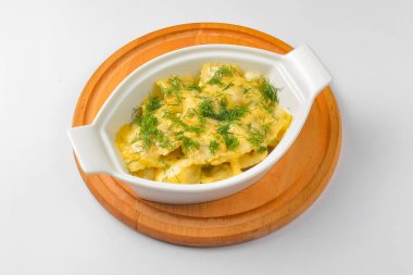 Beyaz arka planda beyaz bir tencerede servis edilen taze yeşillikli Ravioli köftesi. Beyazda izole edilmiş. Geleneksel İtalyan mutfağı.