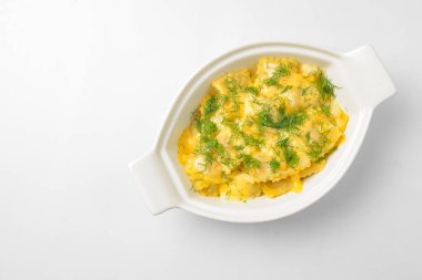 Beyaz arka planda beyaz bir tencerede servis edilen taze yeşillikli Ravioli köftesi. Beyazda izole edilmiş. Geleneksel İtalyan mutfağı.