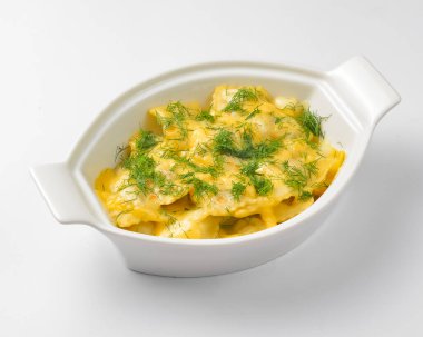 Beyaz arka planda beyaz bir tencerede servis edilen taze yeşillikli Ravioli köftesi. Beyazda izole edilmiş. Geleneksel İtalyan mutfağı.