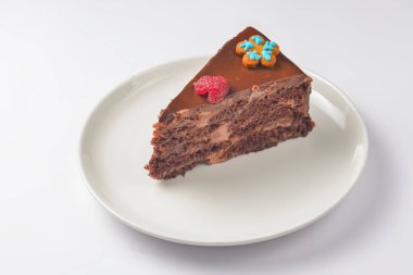 Beyaz tabakta çikolatalı pasta. Beyaz arka planda servis edilen bir parça yumuşak kremalı çikolatalı pasta. Beyazda izole edilmiş. Çay ya da kahve için lezzetli tatlı..