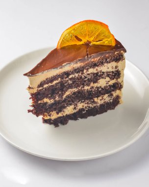 Beyaz tabakta çikolatalı pasta. Beyaz arka planda servis edilen bir parça yumuşak kremalı çikolatalı pasta. Beyazda izole edilmiş. Çay ya da kahve için lezzetli tatlı..