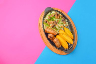 Fırında patatesli ızgara biftek ve mantarlı yeşil salata. Lezzetli bir akşam yemeği. Düz, üst görünüm, renkli pembe ve mavi arkaplan.