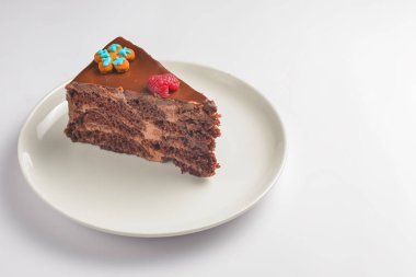 Beyaz tabakta çikolatalı pasta. Beyaz arka planda servis edilen bir parça yumuşak kremalı çikolatalı pasta. Beyazda izole edilmiş. Çay ya da kahve için lezzetli tatlı..