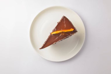 Beyaz tabakta çikolatalı pasta. Beyaz arka planda servis edilen bir parça yumuşak kremalı çikolatalı pasta. Beyazda izole edilmiş. Çay ya da kahve için lezzetli tatlı..