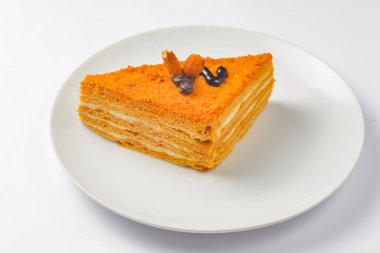 Beyaz arka planda beyaz bir tabakta servis edilen katmanlı bir parça bal keki. Beyazda izole edilmiş. Çay ya da kahve için lezzetli tatlı..