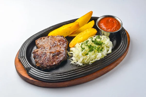 Fırında patatesli ızgara biftek ve sos soslu yeşil salata. Lezzetli bir akşam yemeği. Düz, üst görünüm, beyaz arkaplan üzerinde.