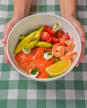 Taze salata, deniz ürünleri, domates ve otlar. Kırmızı somon, küçük karides, avokado, vişneli domates. Yemek için lezzetli bir konsept..