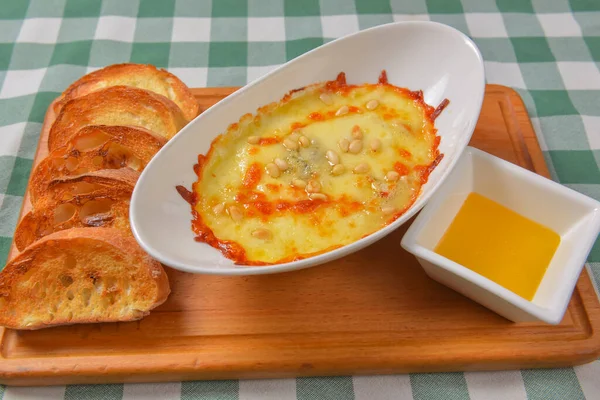 Zucchini baked with cheese in a dish, close up food. Delicious meat and cheese casserole. Italian cuisine concept, green plaid table cloth.