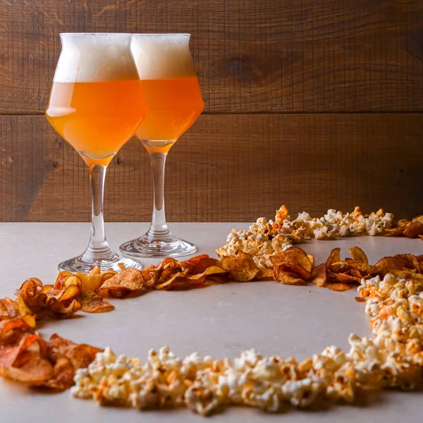 Two glass of beer and beer snacks over white and wooden background. Potato chips and popcorn shaped like an 8. March congratulation, womens day.