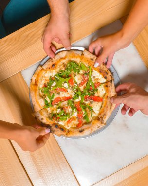 Arkadaş ellerinin pizza dilimlerini alırken görüntüsü. Üst manzara, düz yatış. İtalyan mutfağı konsepti, restoranda lezzetli pizza yemek. Konsepti tüketiyorum.