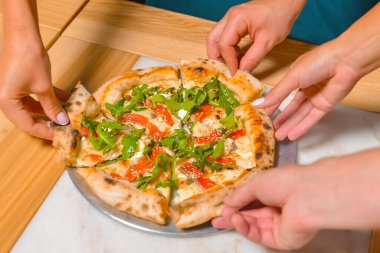 Arkadaş ellerinin pizza dilimlerini alırken görüntüsü. Üst manzara, düz yatış. İtalyan mutfağı konsepti, restoranda lezzetli pizza yemek. Konsepti tüketiyorum.