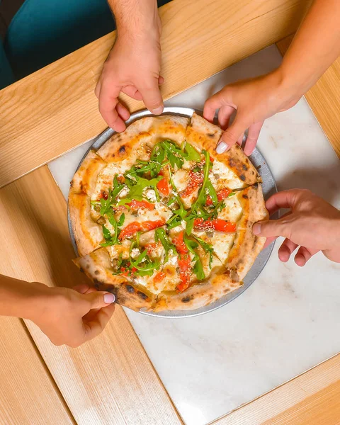 Arkadaş ellerinin pizza dilimlerini alırken görüntüsü. Üst manzara, düz yatış. İtalyan mutfağı konsepti, restoranda lezzetli pizza yemek. Konsepti tüketiyorum.