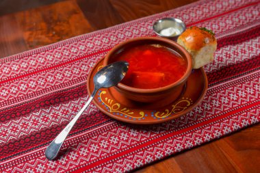 Ukrayna pancar çorbası - ekşi kremalı borş, geleneksel kırmızı masa örtüsü arka planında servis ediliyor. Geleneksel Ukrayna mutfağı kavramı.