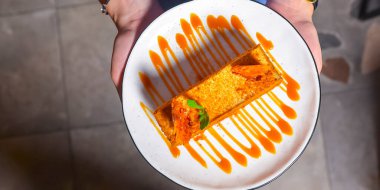 Tabakta ballı kek. Restorandaki ya da kafedeki garson elinde bir parça ballı kek tutuyor. Çay ya da kahve için lezzetli bir tatlı. Restoran servisi..