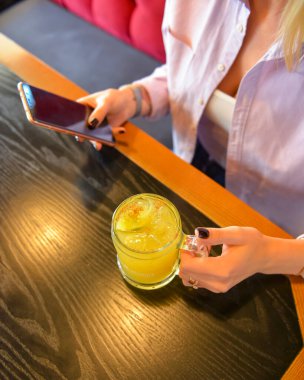 Barda ya da restoranda kokteyl içen çekici bir kız. Durgun hayat, ferahlatıcı alkol içeceği. Barda meyveli içecek. Masada oturan genç bayan..