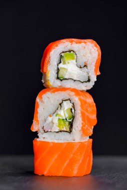 Canlı suşi seti, yaratıcı fikir. Suşi kulesi, Kaliforniya ya da Philadelphia suşi ruloları. Geleneksel Japon mutfağı kavramı. Susam tohumları serpiştirilmiş. Siyah arkaplanda.