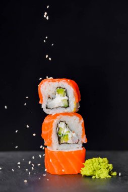 Canlı suşi seti, yaratıcı fikir. Suşi kulesi, Kaliforniya ya da Philadelphia suşi ruloları. Geleneksel Japon mutfağı kavramı. Susam tohumları serpiştirilmiş. Siyah arkaplanda.