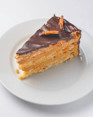 Beyaz izole edilmiş arka planda kremalı vanilyalı ve çikolatalı kek. Beyaz tabakta servis edilmiş. Çay ya da kahve için lezzetli bir tatlı..