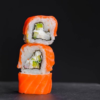 Canlı suşi seti, yaratıcı fikir. Suşi kulesi, Kaliforniya ya da Philadelphia suşi ruloları. Geleneksel Japon mutfağı kavramı. Susam tohumları serpiştirilmiş. Siyah arkaplanda.