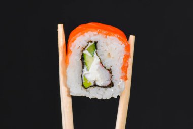 Canlı suşi seti, yaratıcı fikir. Çubuklu suşi, California ya da Philadelphia suşisi. Geleneksel Japon mutfağı kavramı. Susam tohumları serpiştirilmiş. Siyah arkaplanda.