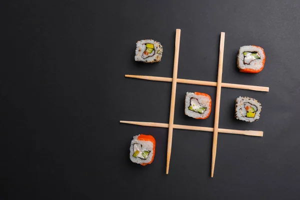 Siyah arka planda suşi, yaratıcı konsept suşi ruloları olan Tic Tac toe oyunu. Banner, tic tac toe oyunu oynuyor. Japon mutfağı konsepti, suşi reklamı..