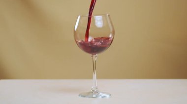 Şarap kadehini süper yavaş çekimde kırmızı şarapla doldurun. Bir bardağa kırmızı şarap dolduruyorum. Kırmızı şarap camda güzel bir dalga oluşturur..